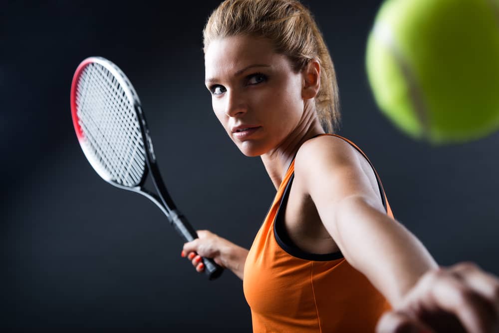 ラケットを手にテニスボールを打ち返すべきリターンを狙う女性の真剣な表情。